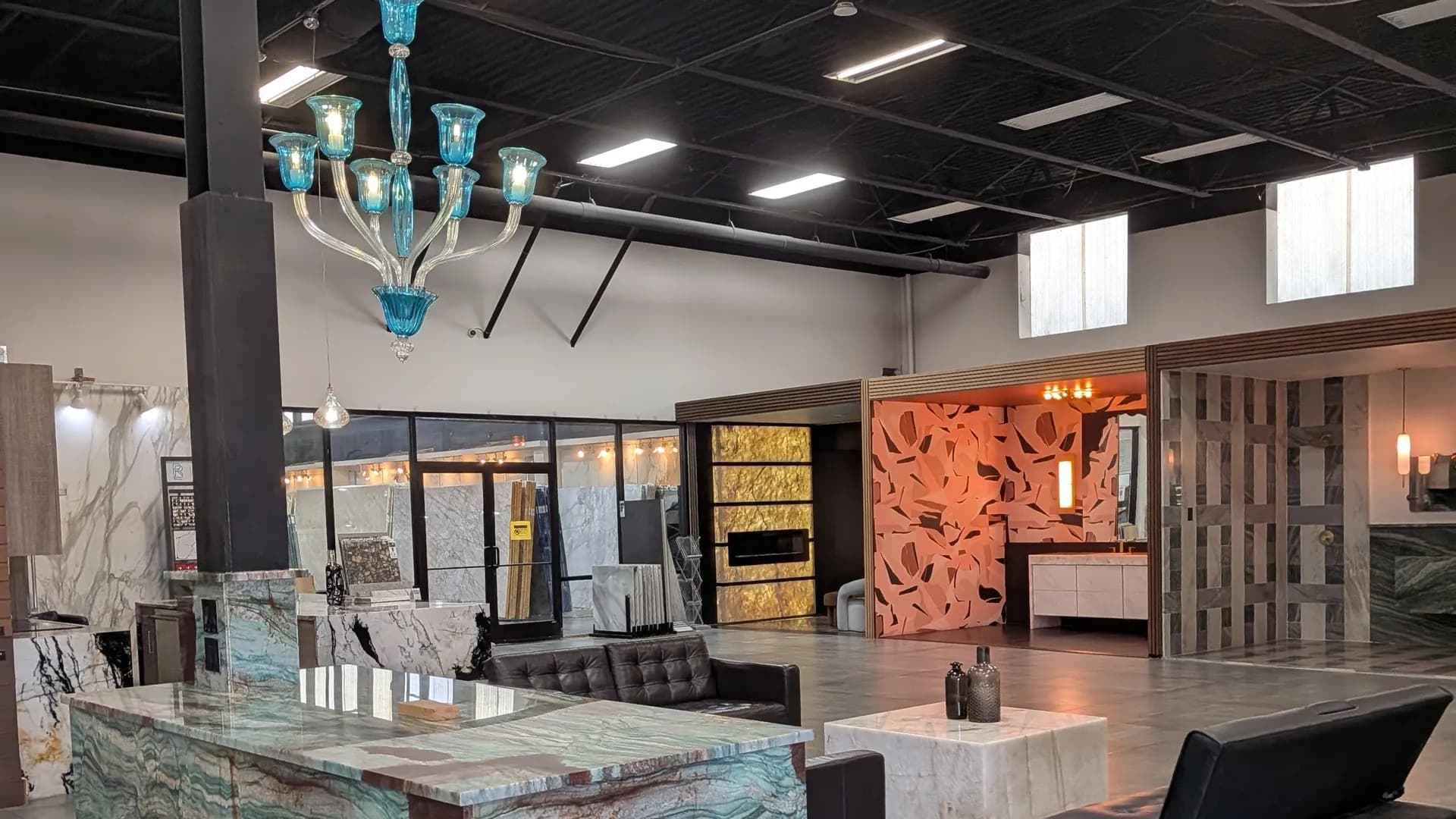 The KLZ showroom floor under a turquoise glass chandelier, with stone islands and a backlit wall