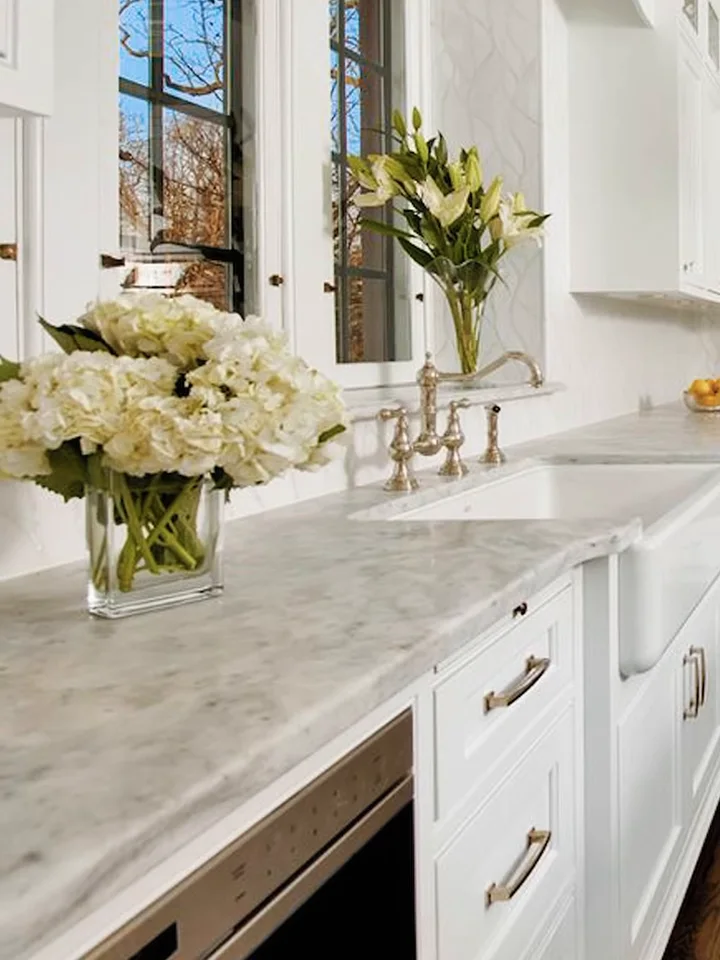 A double vanity run in soft grey marble beneath a window