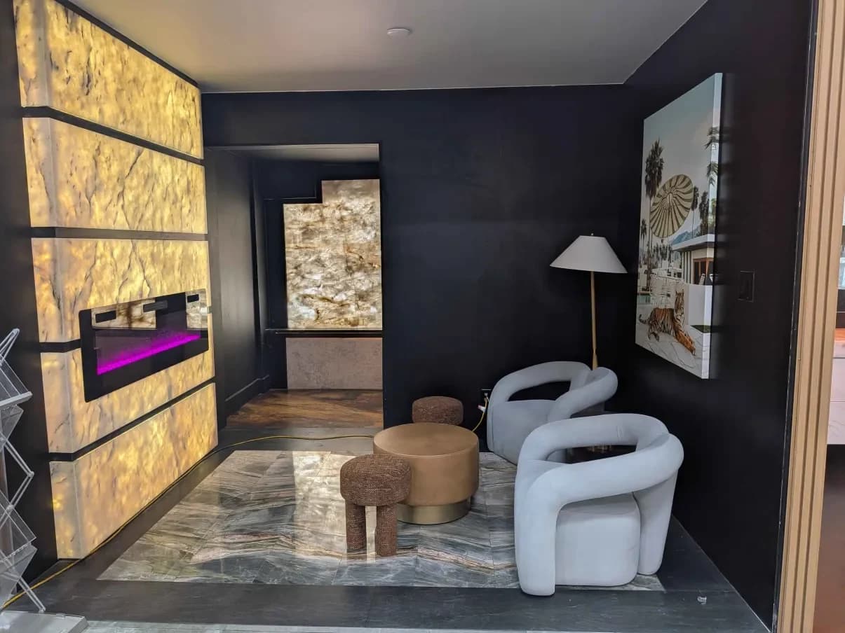 A dark showroom lounge walled in backlit stone panels