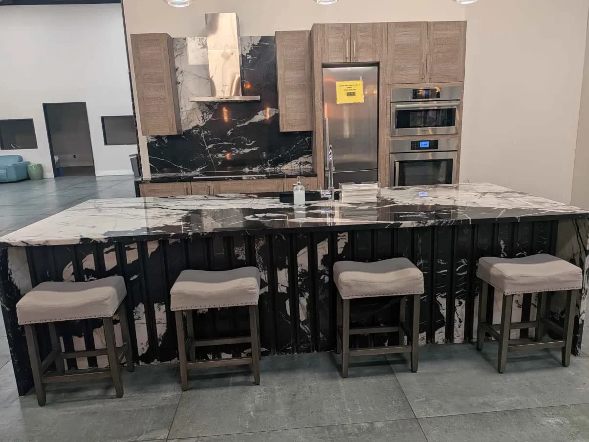 A showroom kitchen in black and gold marble with a waterfall island
