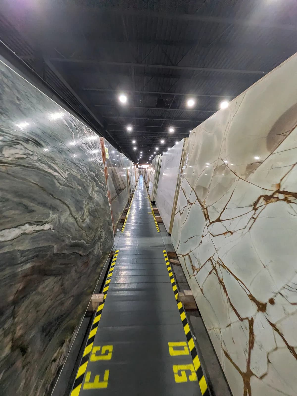 Polished slabs with gray and brown veining on both sides of a long aisle